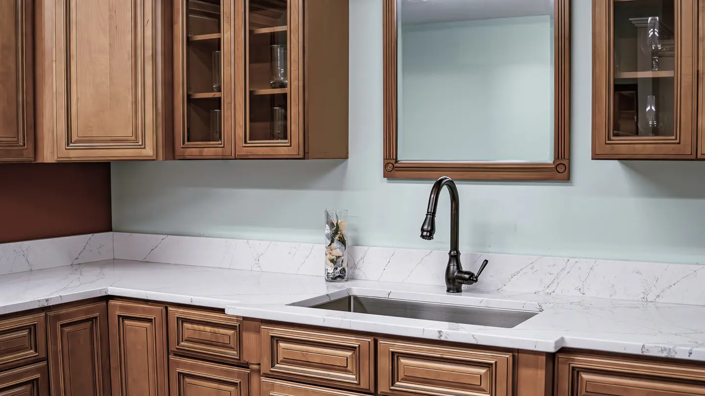White marble-look quartz countertops with undermount sink and traditional brown cabinets in a New Hampshire kitchen — templated and installed by Precision Granite Works