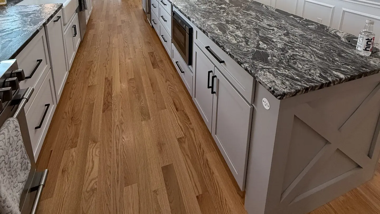 Dramatic dark granite countertops with bold silver veining installed on a farmhouse-base island and perimeter cabinets in a New Hampshire kitchen — by Precision Granite Works