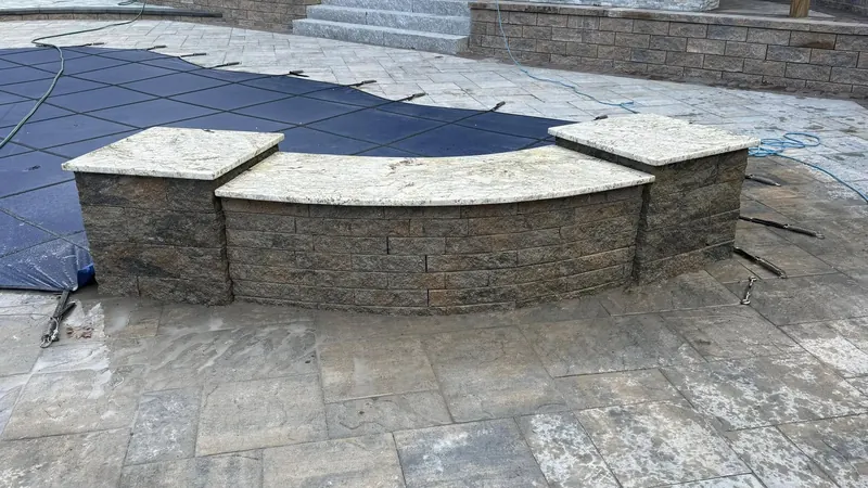Custom curved granite wall caps on a stone veneer pool surround — precision-cut and installed in New Hampshire by Precision Granite Works