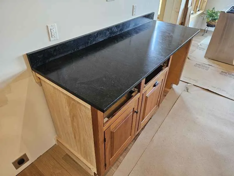 Long honed soapstone countertop work surface with subtle mineral movement and matching backsplash
