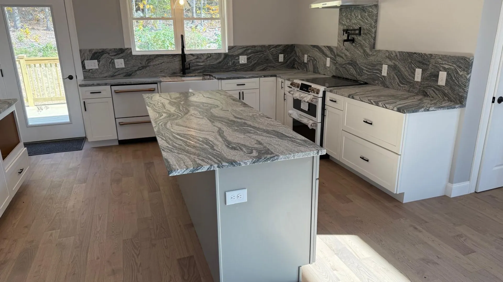 Custom granite kitchen countertops with dramatic swirl pattern on island and perimeter — fabricated and installed in New Hampshire by Precision Granite Works