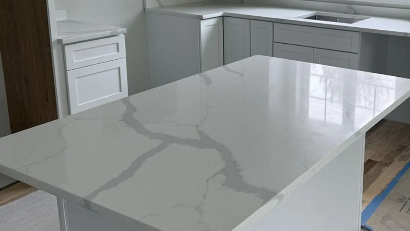 Large white quartz island with Calacatta-style grey veining in a New Hampshire kitchen