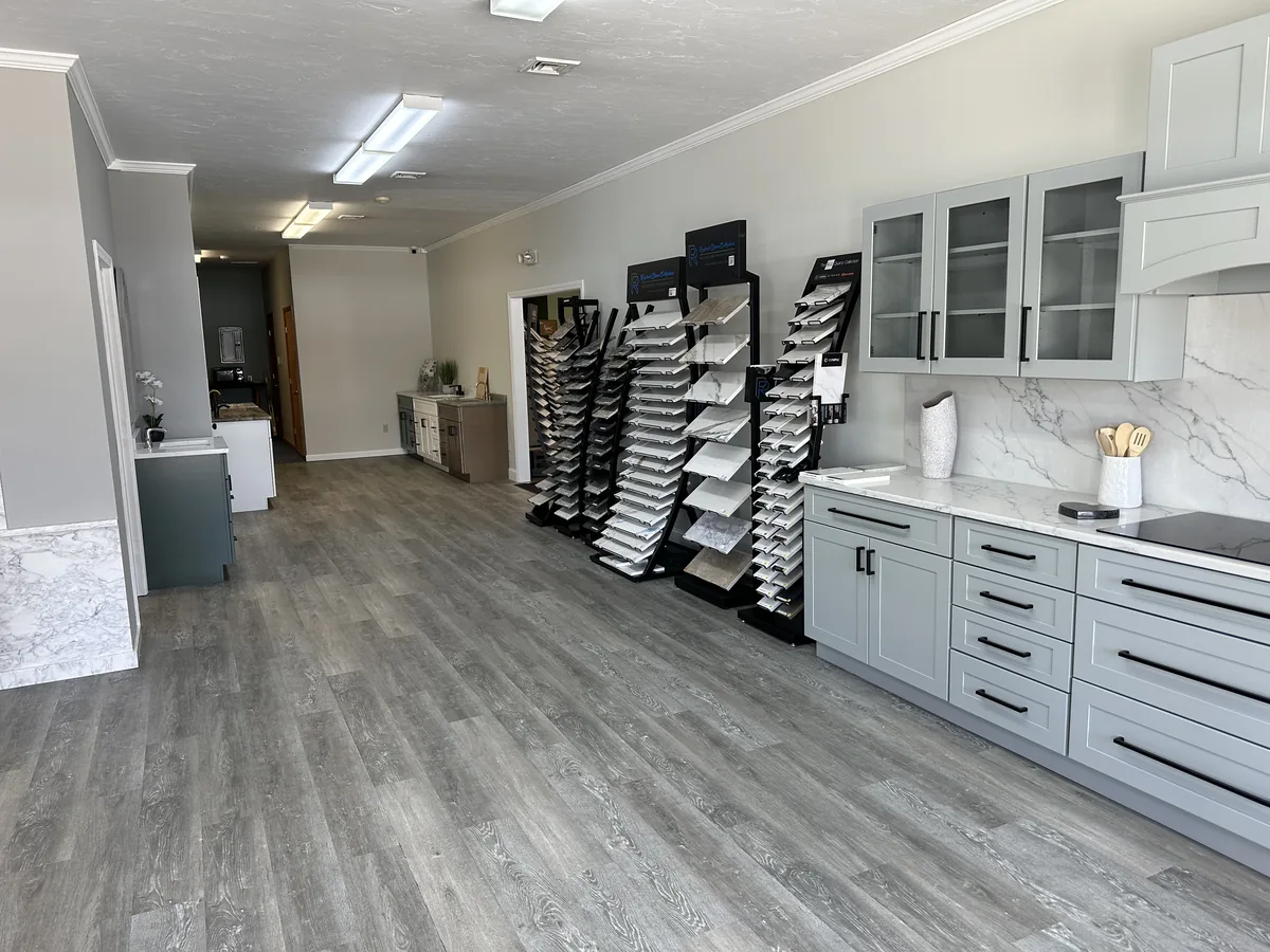 Inside the Precision Granite Works showroom in Epsom NH — granite, quartz, and marble sample racks alongside a finished kitchen display with stone countertops