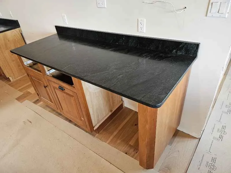 Soapstone breakfast bar countertop with a softened rounded corner over wood cabinets