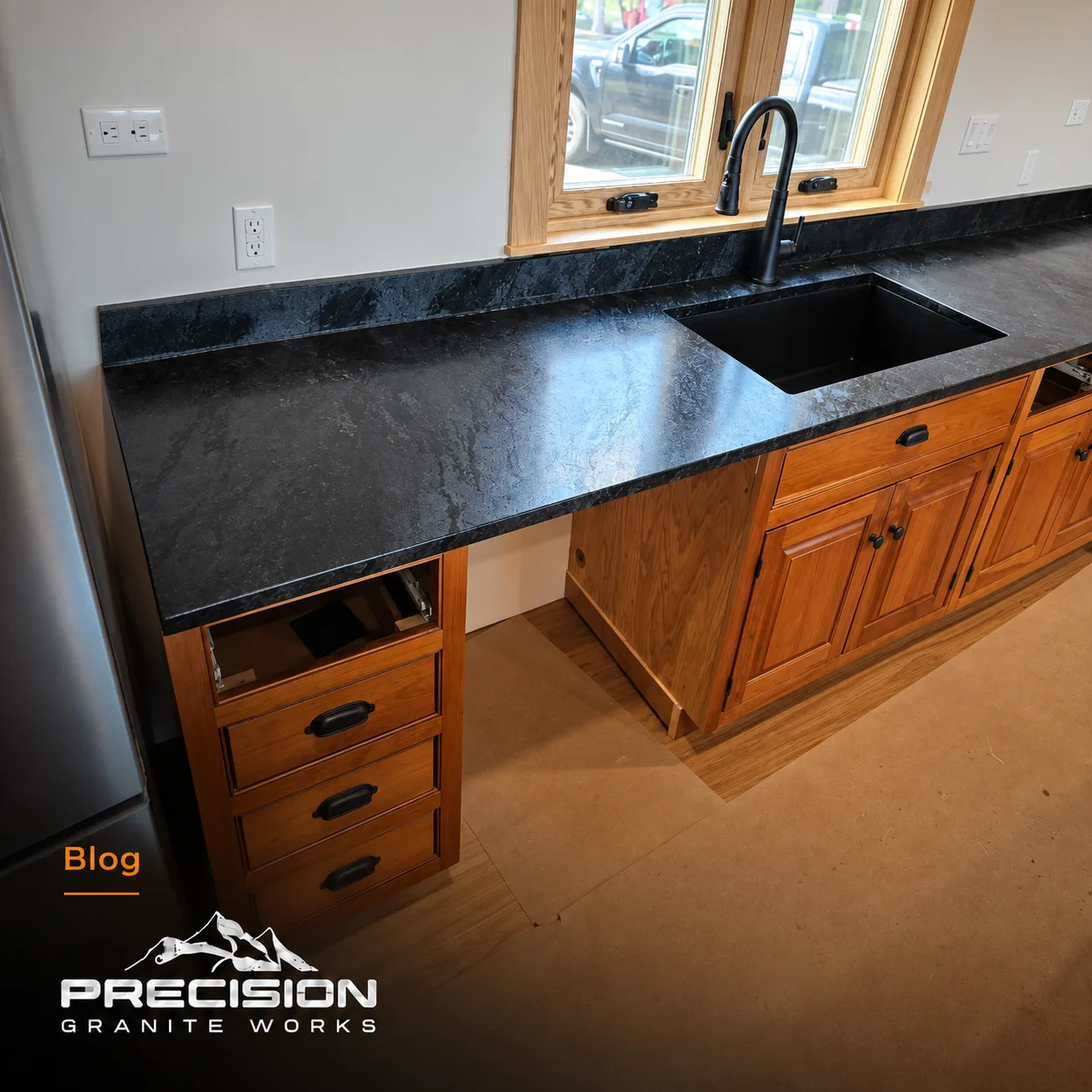 Honed charcoal soapstone kitchen countertop with subtle pale veining and warm wood cabinets